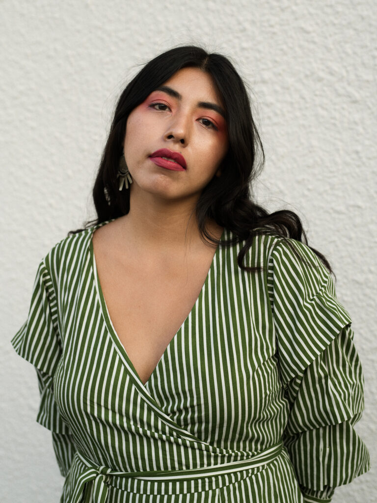 A person looking straight forward wearing a green and white stripy top.